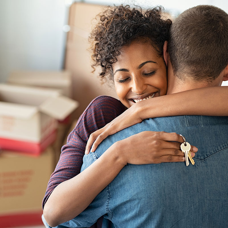 Woman and man embracing; she's holding keys to a new apartment