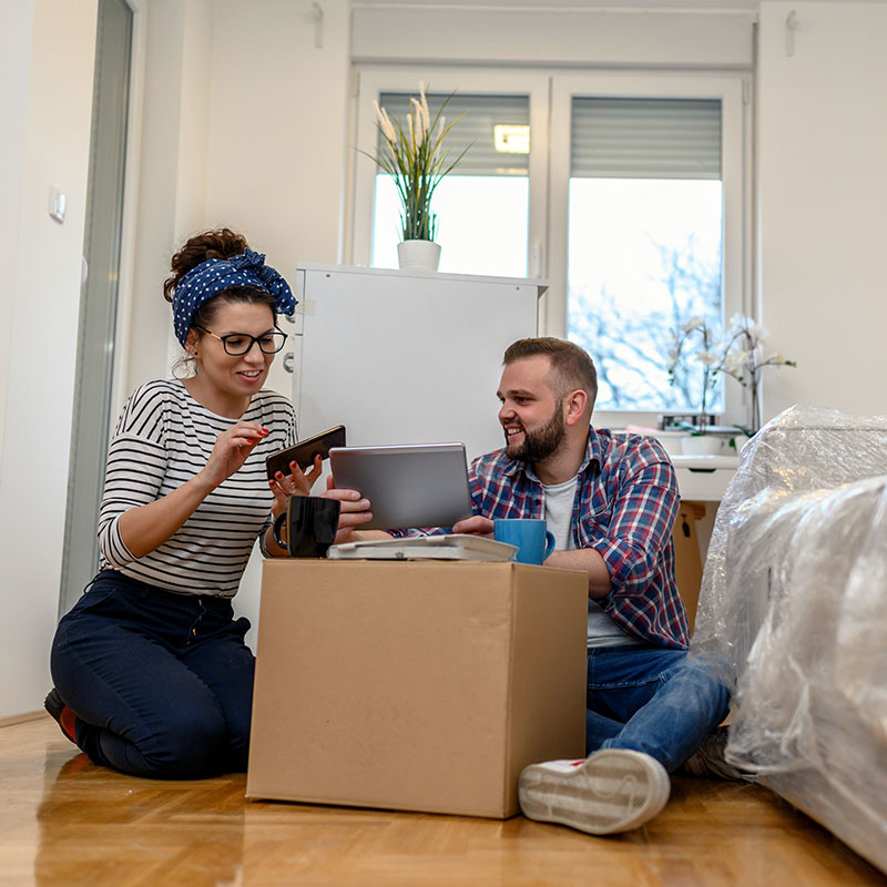 Woman and man sitting on floor; just moved into their new apartment